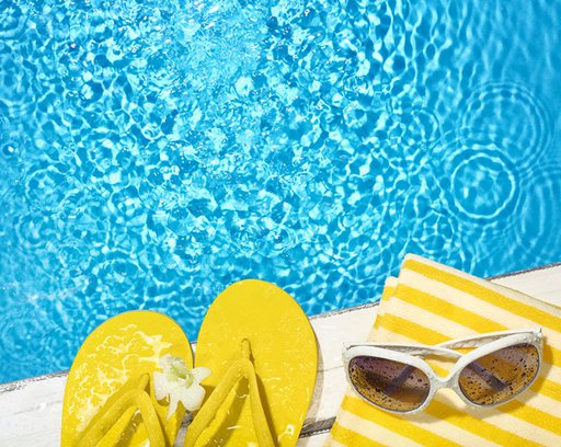Flip flop,towel and sunglasses on the side of a swimming pool
