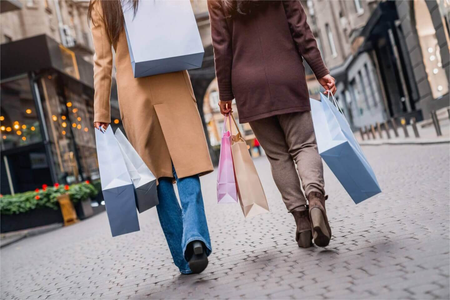 two people walking down the street with shopping bags